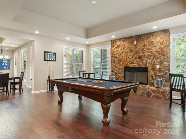a room with wooden floor pool table and windows