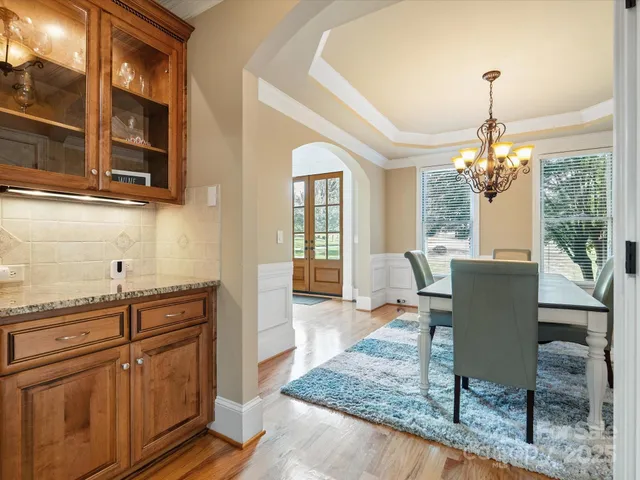 a dining room with wooden floor a chandelier a wooden table and chairs