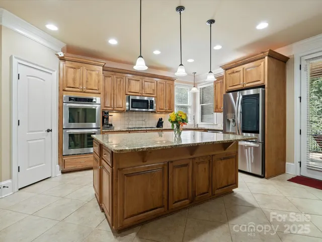 a kitchen with stainless steel appliances granite countertop a sink a stove and a refrigerator