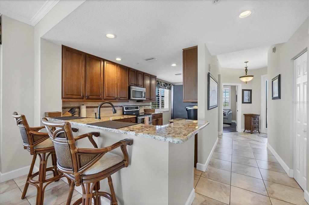 13113 Gasparilla Road, Unit A305 Placida, FL 33946 - Photo 8 of 29 a kitchen with stainless steel appliances kitchen island granite countertop a stove a refrigerator a oven a sink dishwasher and white cabinets with wooden floor