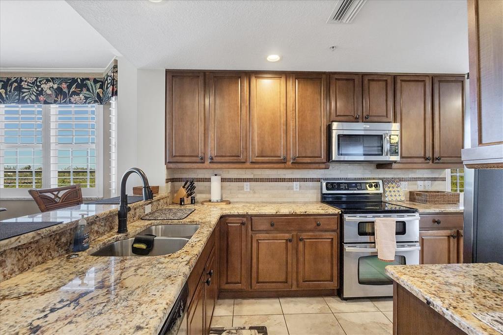 13113 Gasparilla Road, Unit A305 Placida, FL 33946 - Photo 9 of 29 a kitchen with kitchen island granite countertop a sink stove and cabinets