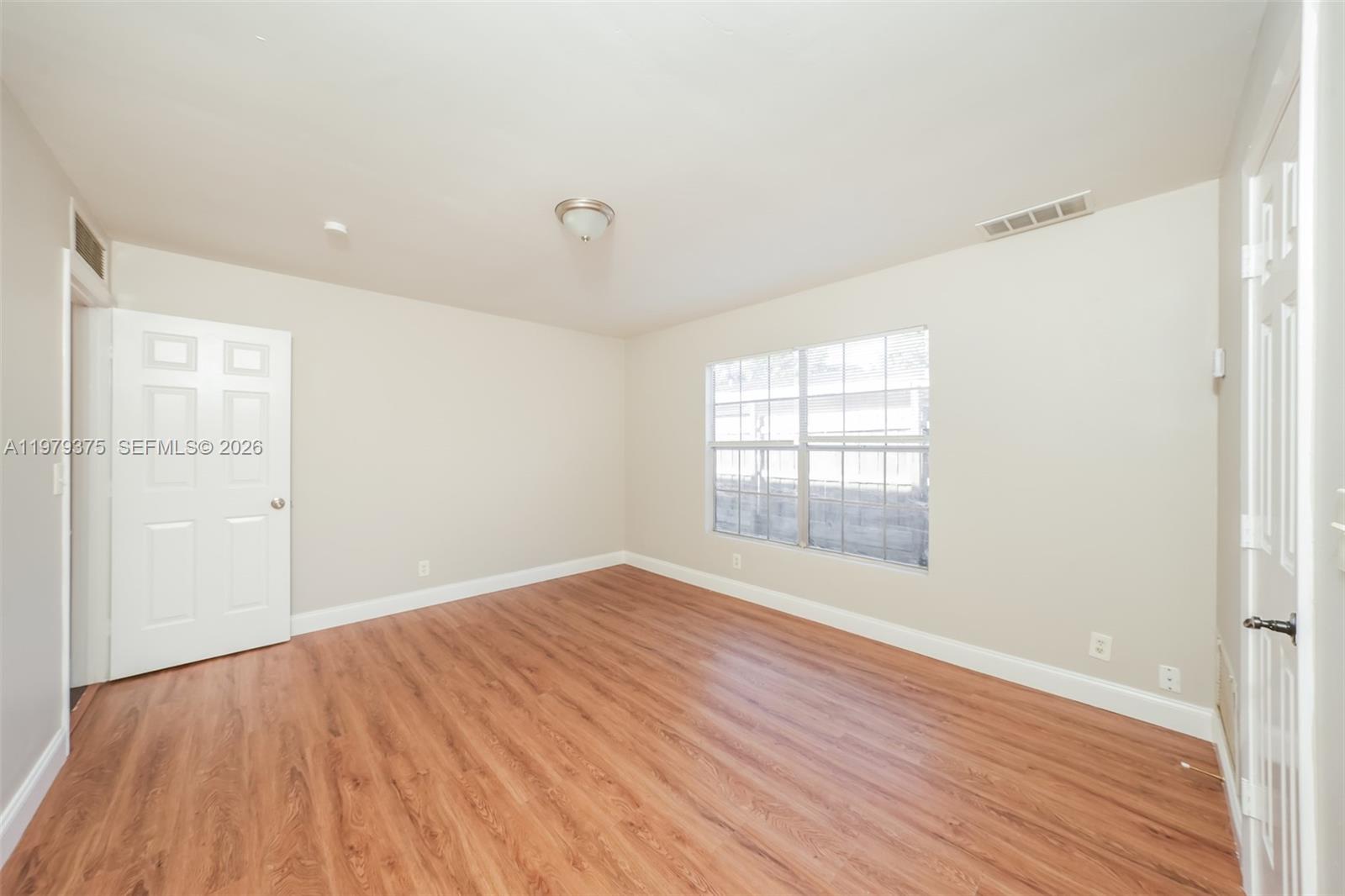 5227 Adams Road Delray Beach, FL 33484 - Photo 10 of 18 an empty room with wooden floor and windows