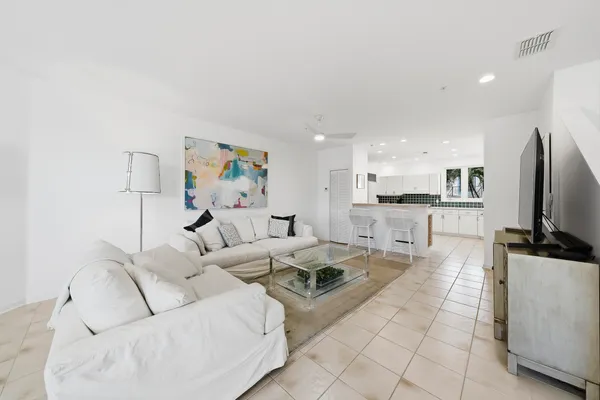 a living room with furniture a flat screen tv and kitchen view