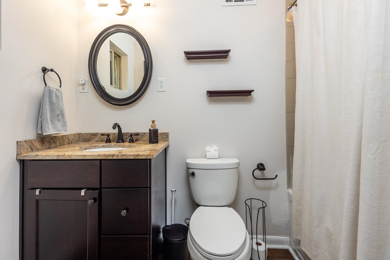 5681 Normandy Road Memphis, TN 38120 - Photo 11 of 22 a bathroom with a toilet a sink a mirror and vanity