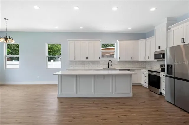 a kitchen with a sink cabinets stainless steel appliances and a window