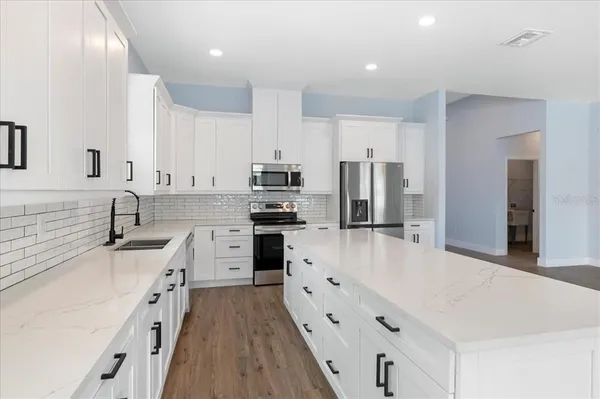 a large kitchen with stainless steel appliances lots of counter space and wooden floor