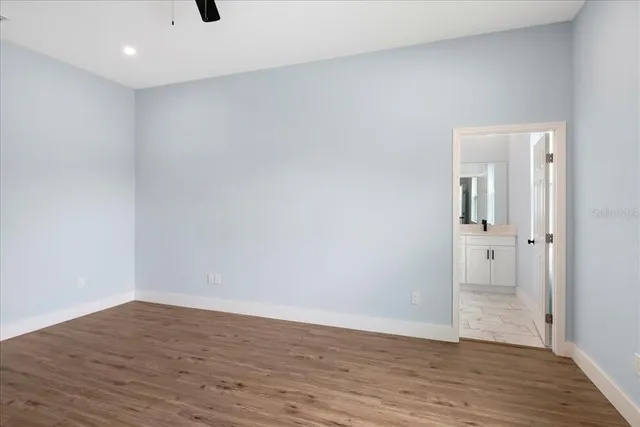 a view of an empty room with wooden floor and a mirror