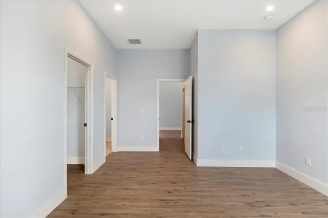 a view of an empty room with wooden floor and closet
