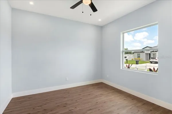an empty room with wooden floor fan and windows