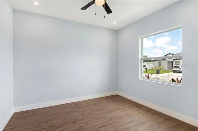an empty room with wooden floor fan and windows