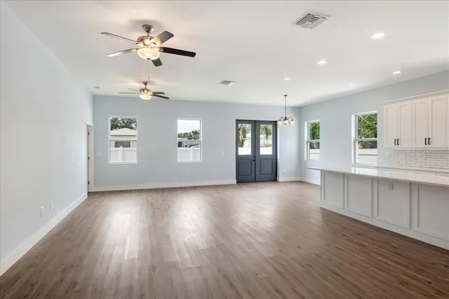 a view of an empty room with a window and wooden floor
