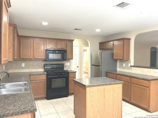 a kitchen with granite countertop a sink stainless steel appliances and cabinets