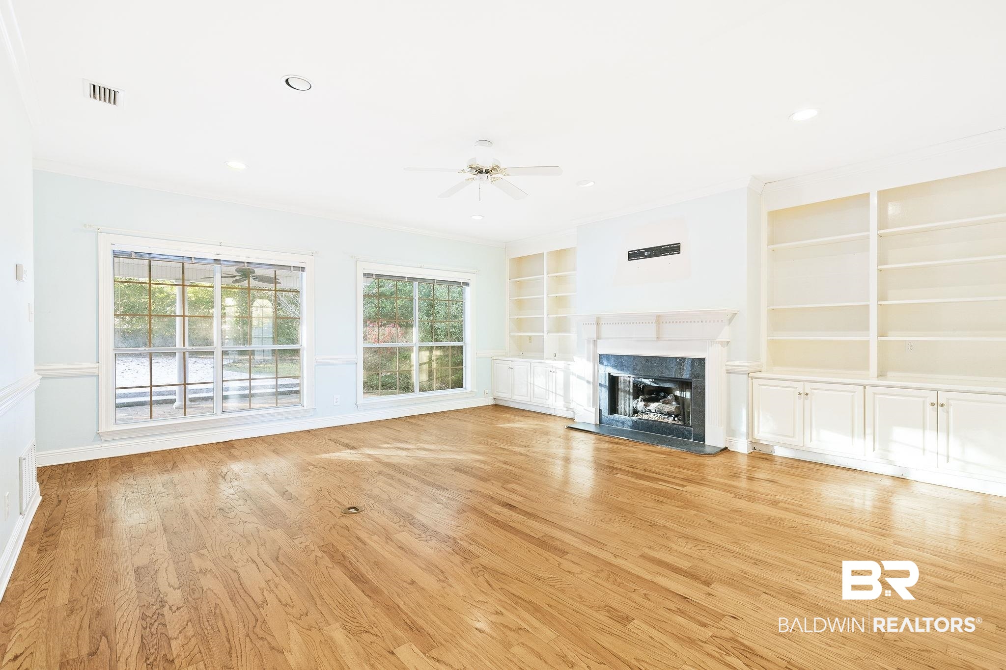 2100 Stonebrook Drive West Mobile, AL 36695 - Photo 10 of 60 Unfurnished living room featuring a high end fireplace, ornamental molding, ceiling fan, light hardwood / wood-style flooring, and built in features