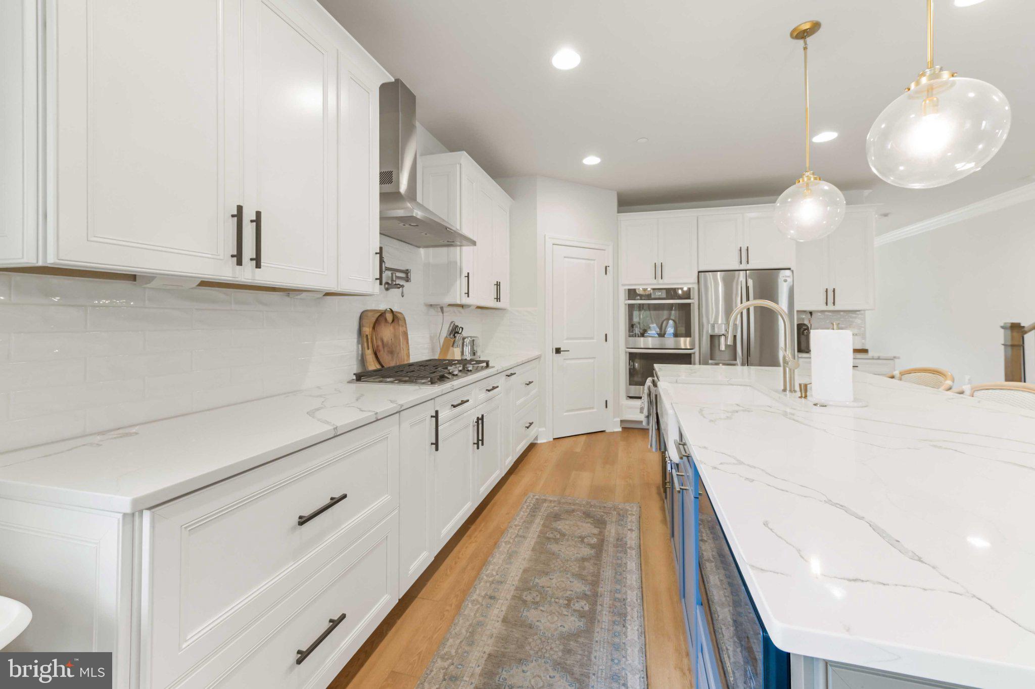 6310 Winters Lane Hanover, MD 21076 - Photo 15 of 76 a large white kitchen with lots of counter space wooden floor and stainless steel appliances