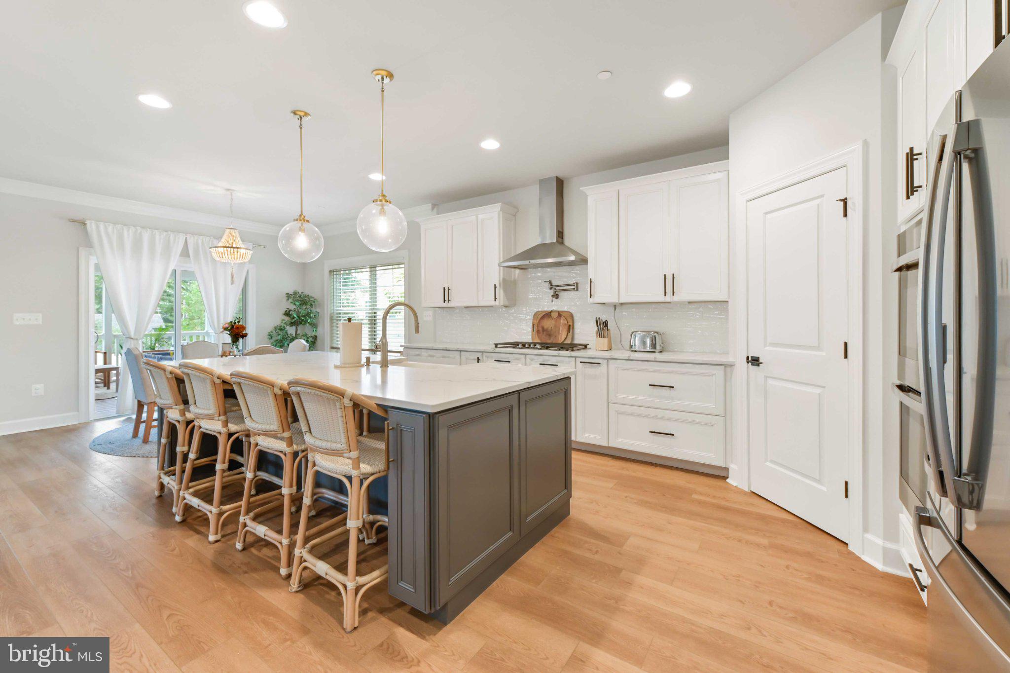 6310 Winters Lane Hanover, MD 21076 - Photo 17 of 76 a kitchen with stainless steel appliances kitchen island granite countertop a table chairs and a refrigerator