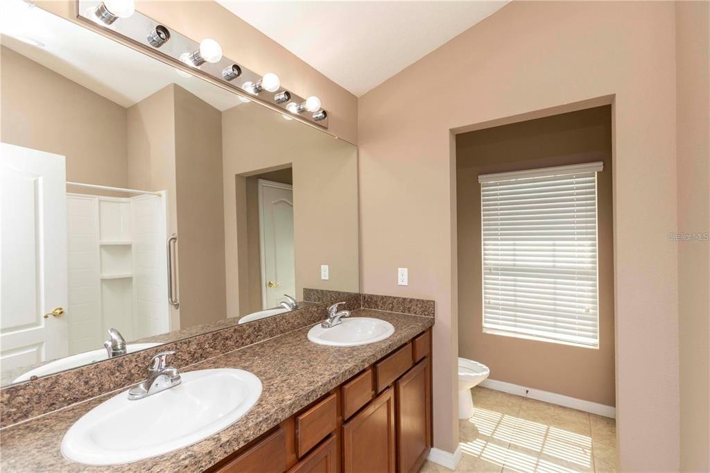8409 Blue Rock Drive New Port Richey, FL 34653 - Photo 22 of 36 a bathroom with a granite countertop sink a large mirror and a toilet
