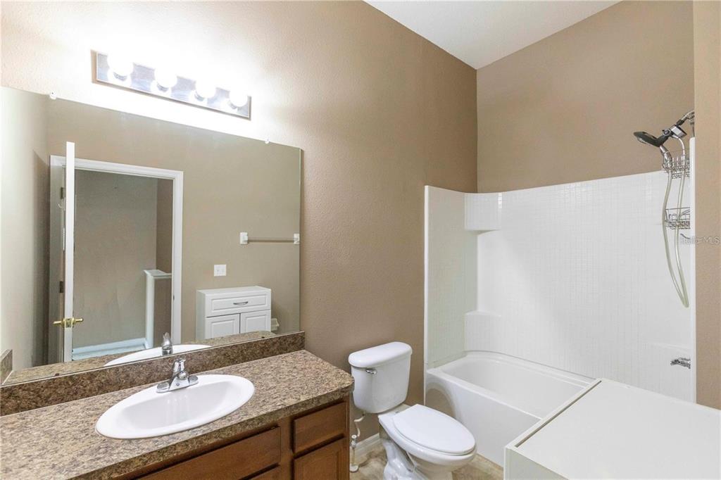 8409 Blue Rock Drive New Port Richey, FL 34653 - Photo 25 of 36 a bathroom with a granite countertop sink a toilet a mirror and shower