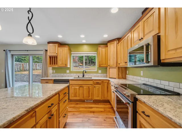 a kitchen with granite countertop a sink a counter top space stainless steel appliances and cabinets