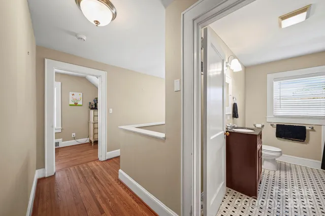 a view of a hallway with wooden floor and a bathroom