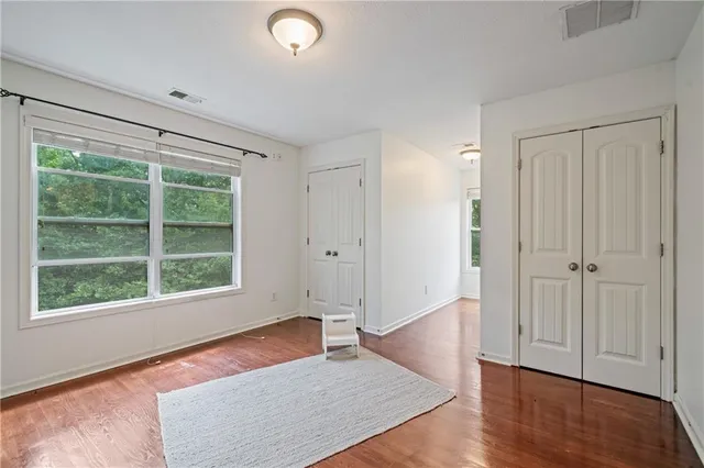 an empty room with wooden floor and windows