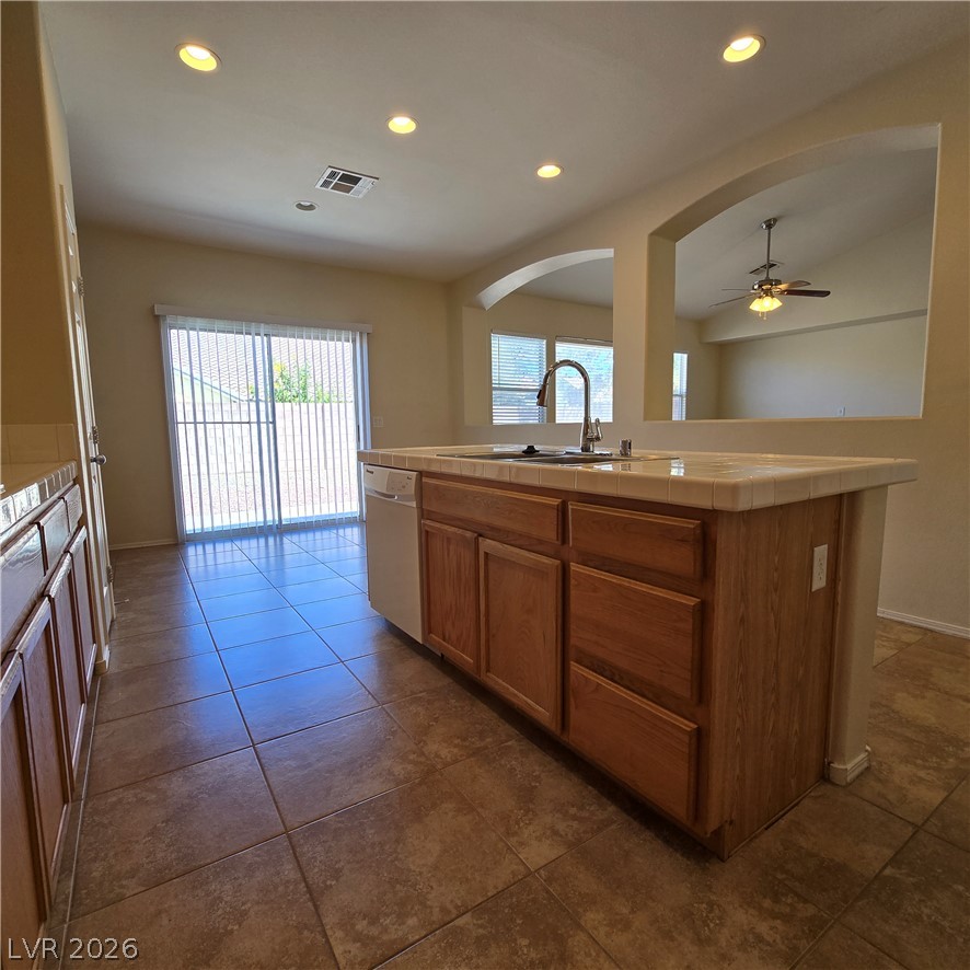 9234 Kingston Road Henderson, NV 89074 - Photo 18 of 38 A well-appointed kitchen island with sink overlooks a bright dining area, featuring practical tiled flooring.