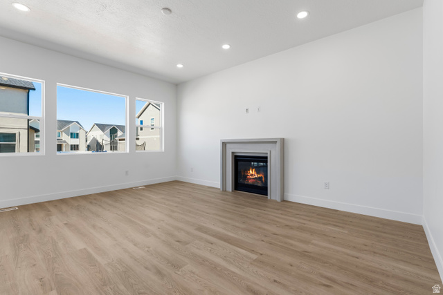 58 South Crimson Way, Unit 306 Mapleton, UT 84664 - Photo 7 of 24 Spacious room featuring wood-finish flooring, a contemporary fireplace with a light gray surround, multiple large windows, recessed lighting, and white baseboards