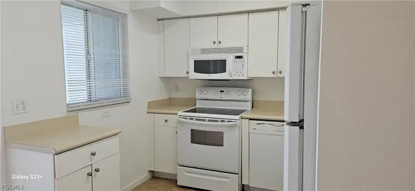 a kitchen with granite countertop white cabinets and white appliances