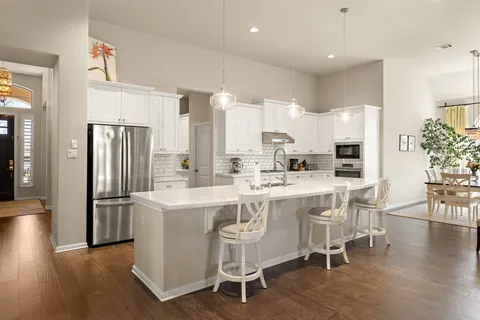a kitchen with stainless steel appliances granite countertop a table chairs refrigerator and sink