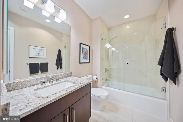 a bathroom with a granite countertop sink a toilet a mirror and shower