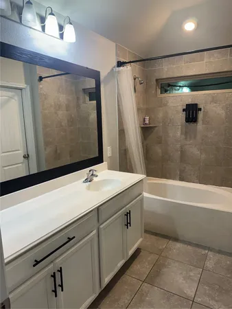 a bathroom with a bathtub sink vanity and mirror