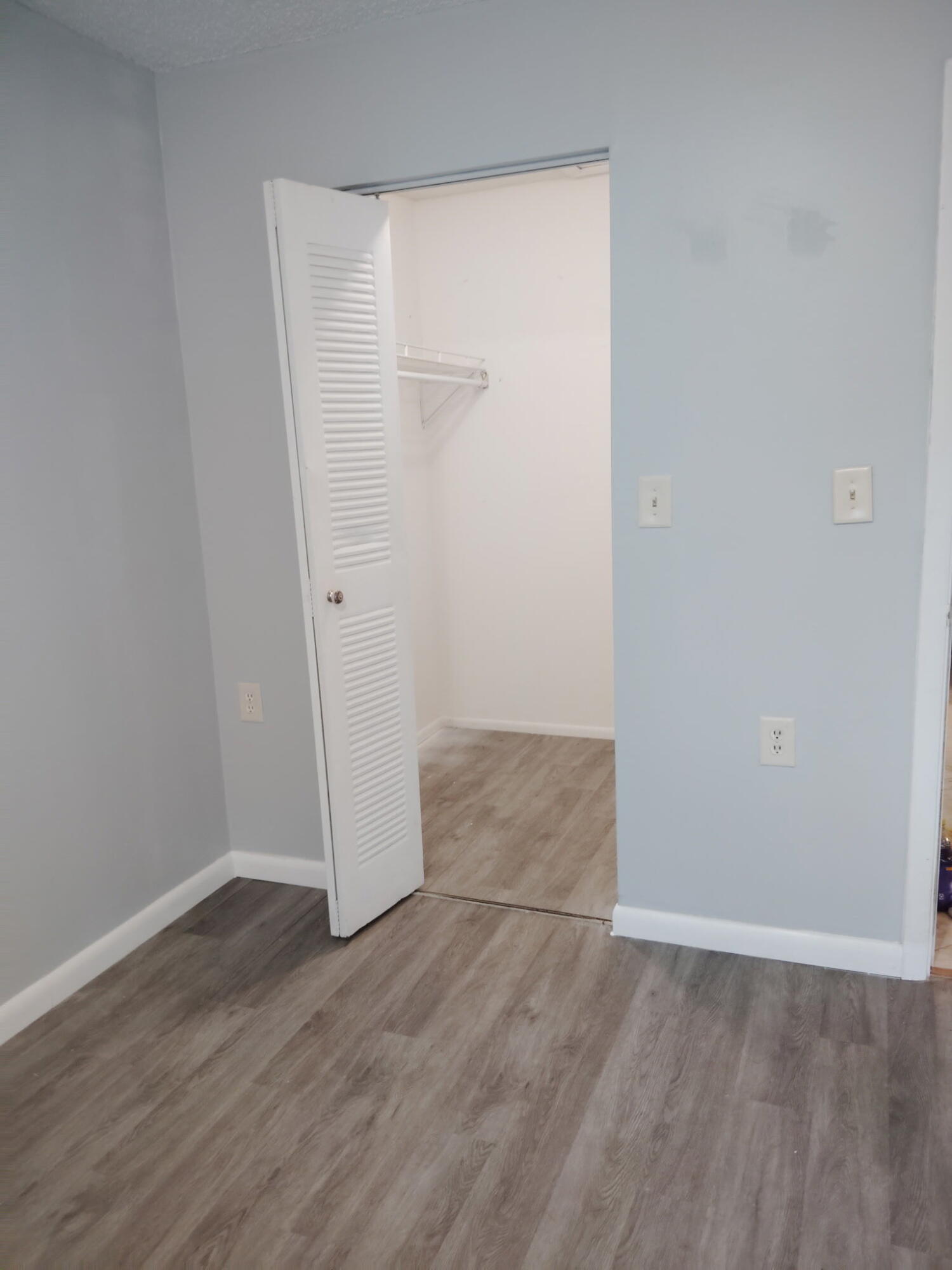 1140 Lake Victoria Drive, Unit M West Palm Beach, FL 33411 - Photo 7 of 8 an empty room with wooden floor and mirror