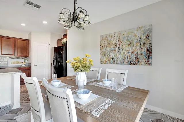 a view of a dining room with furniture a kitchen and chandelier