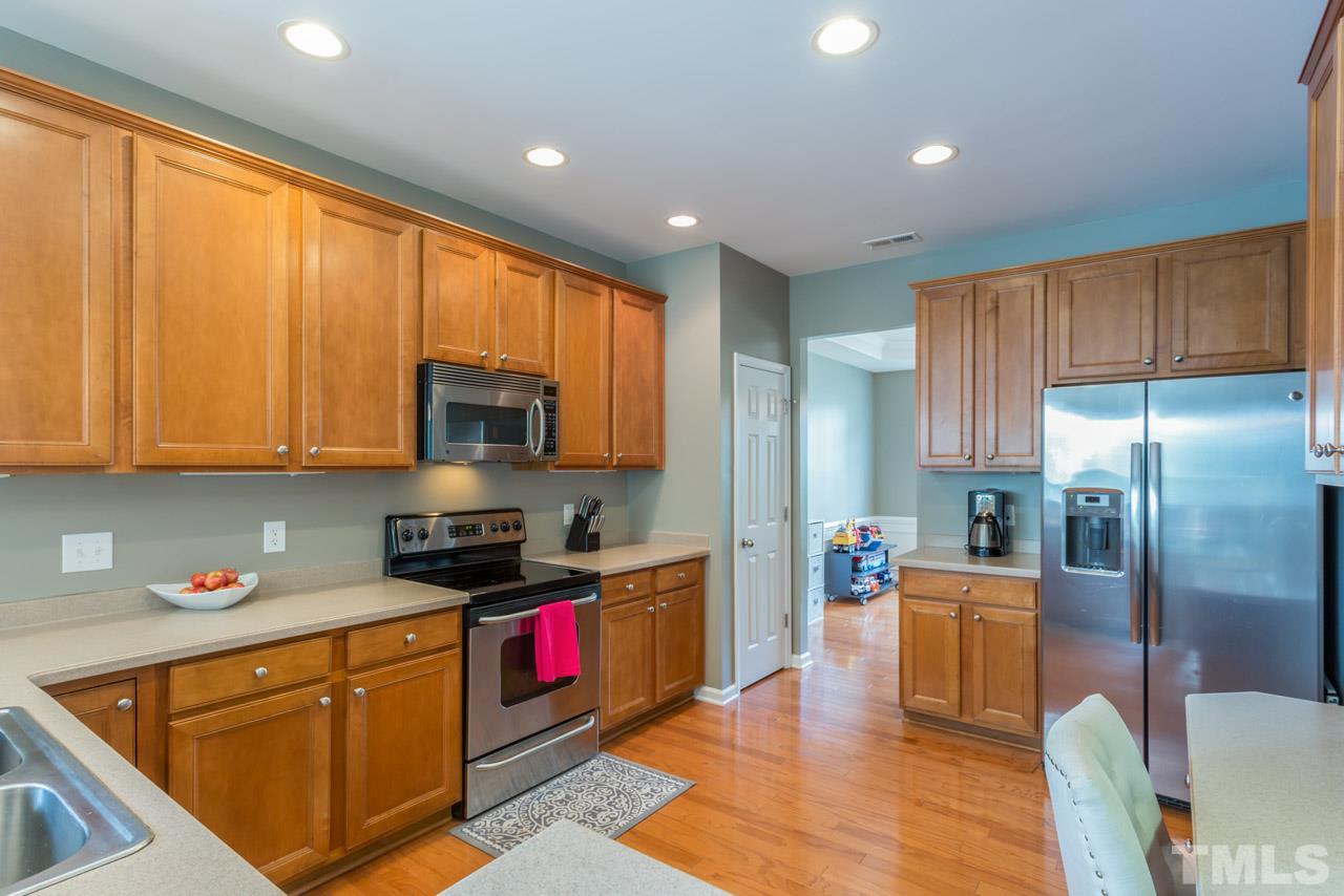 5331 Shaker Heights Lane Raleigh, NC 27613 - Photo 7 of 25 a kitchen with stainless steel appliances granite countertop a refrigerator a sink dishwasher a stove and a dining table with wooden floor