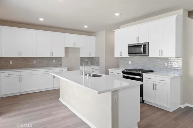 a kitchen with stainless steel appliances white cabinets a sink and a stove