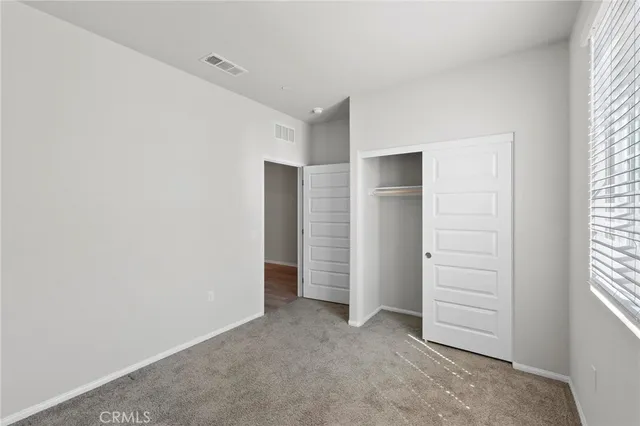 an empty room with a window and a kitchen