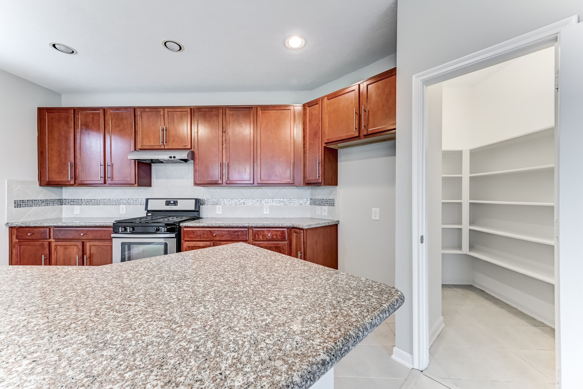 4706 Mint Trail Houston, TX 77066 - Photo 12 of 43 a kitchen with stainless steel appliances granite countertop wooden cabinets a stove top oven a sink and dishwasher