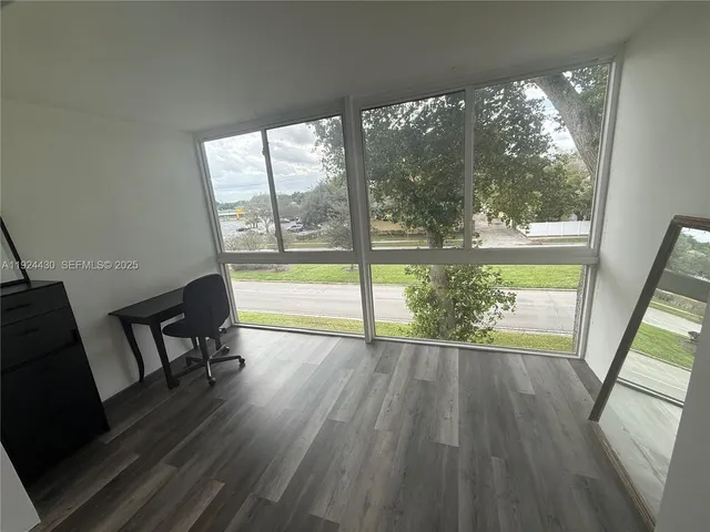 a view of an empty room with wooden floor and a chair