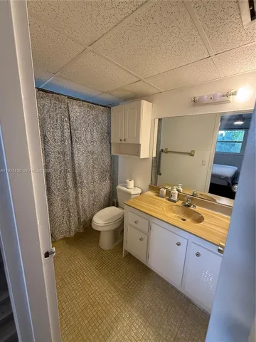 a bathroom with a granite countertop sink a toilet a mirror and shower