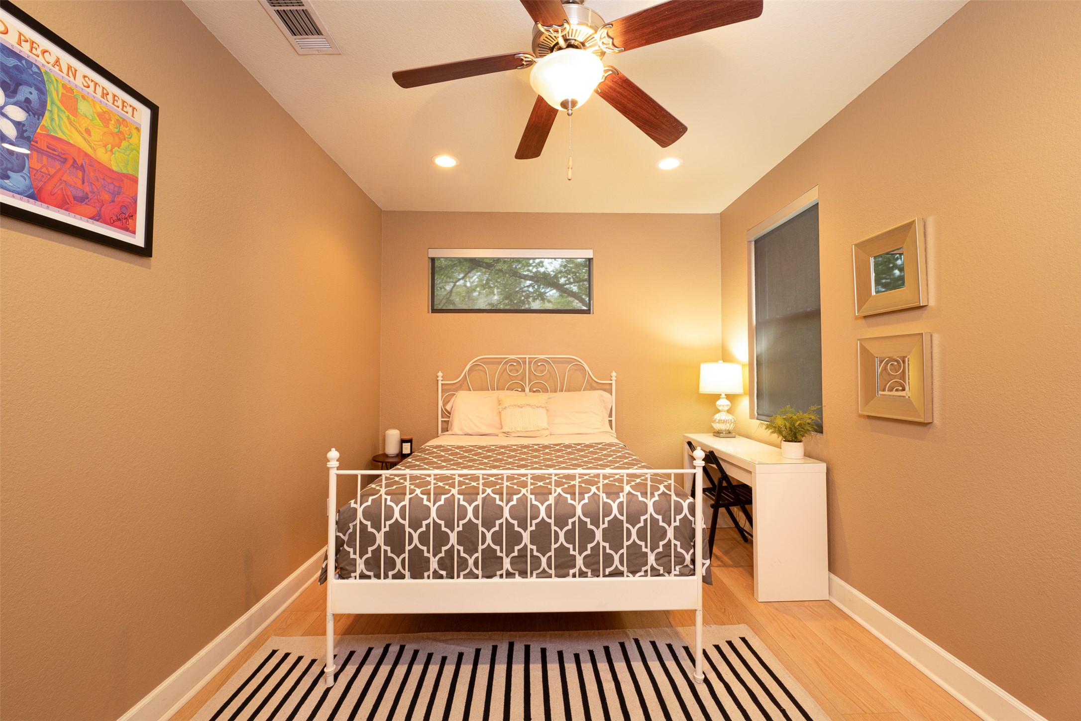 2302 East 9th Street Austin, TX 78702 - Photo 25 of 31 A well-lit room features a decorative bed, a ceiling fan, and hardwood floors.
