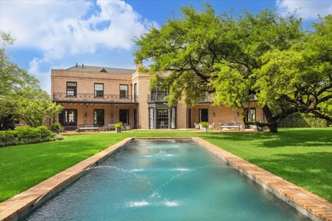 a view of a big building with a big yard and large trees