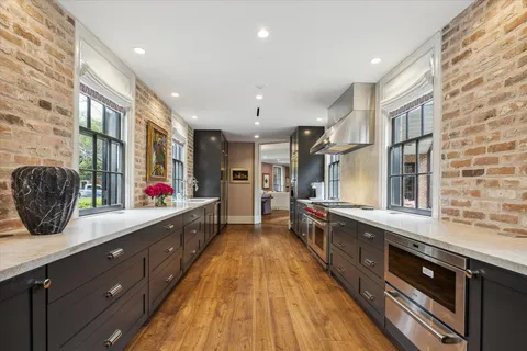 a large kitchen with stainless steel appliances a large counter top a stove a chimney a sink and a large window