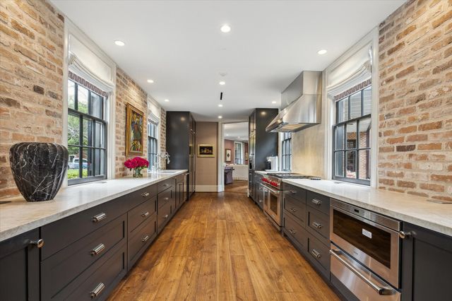 a large kitchen with stainless steel appliances a large counter top a stove a chimney a sink and a large window