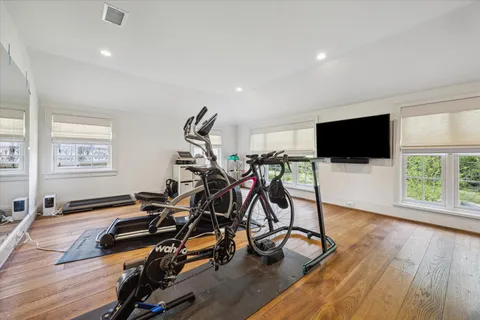 a view of a room with gym equipment and wooden floor