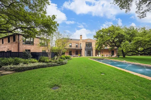 a view of a house next to a big yard and large trees