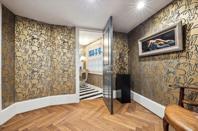 a view of a hallway with wooden floor and a bathroom