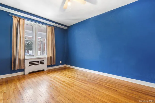 a view of an empty room with a window and wooden floor