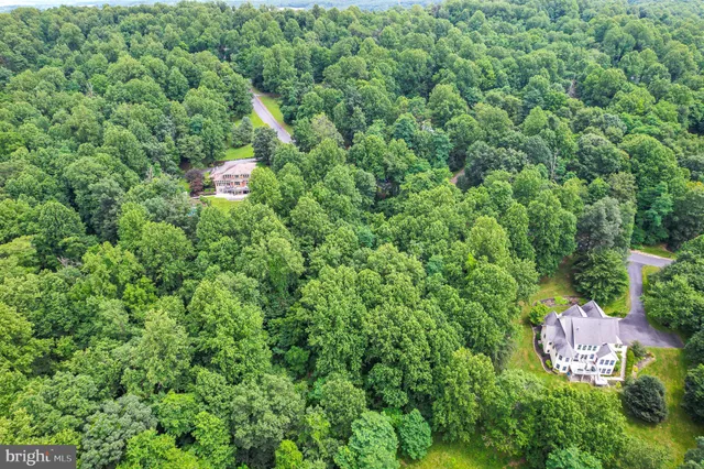 an aerial view of residential house with outdoor space and trees all around