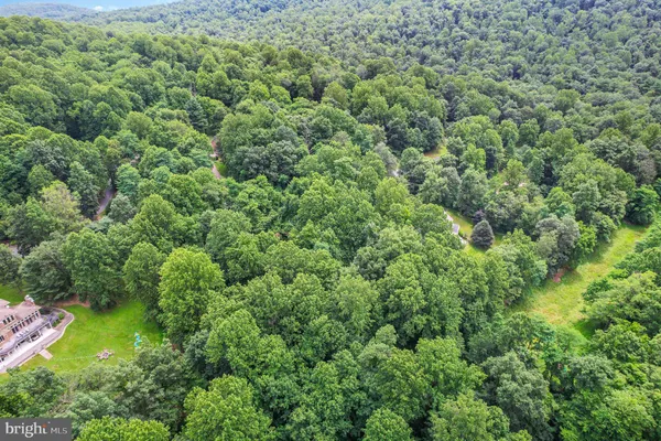 an aerial view of residential house with outdoor space and trees all around