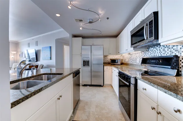 a kitchen with granite countertop a refrigerator stove top oven and sink