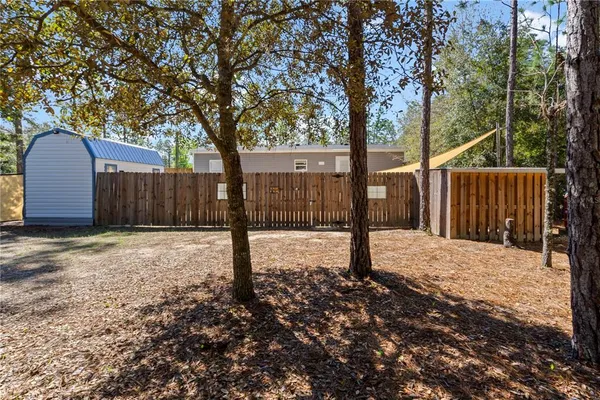 a view of a backyard with large trees and wooden fence